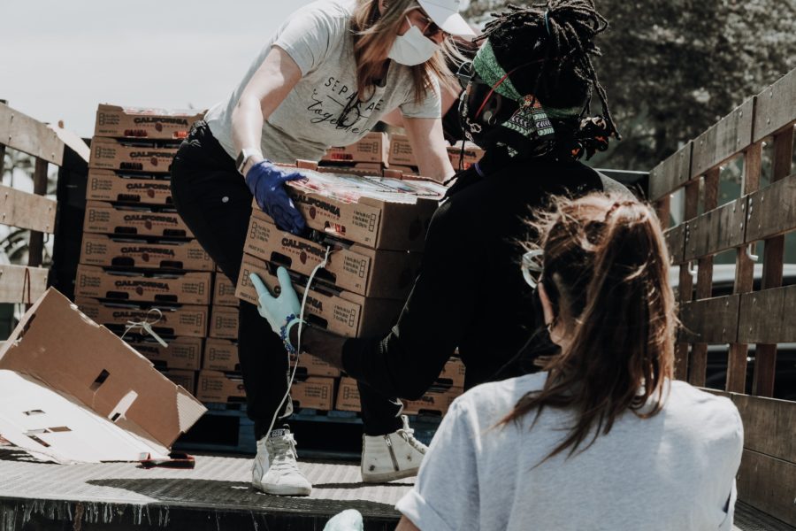 A group of volunteers unloading boxes of food off the back of a pickup truck.